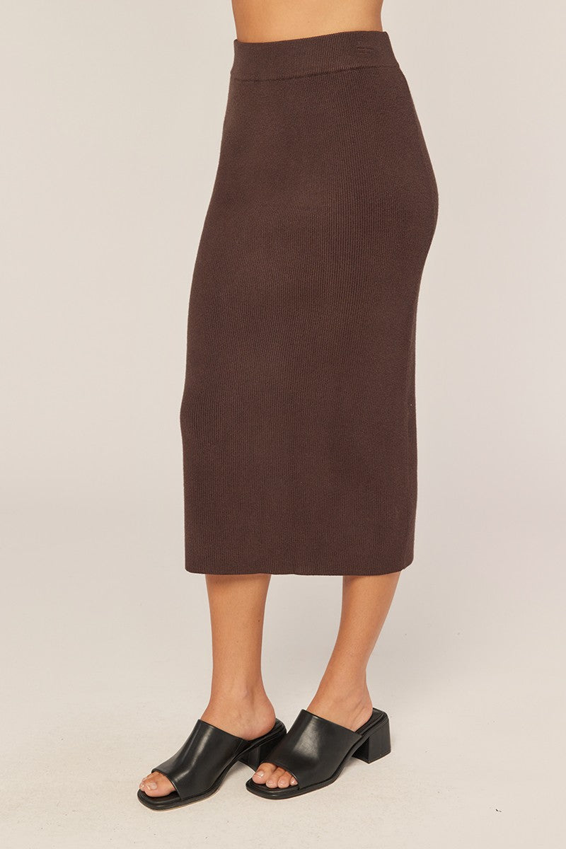 woman wearing a dark brown ribbed midi skirt and black open-toe mules