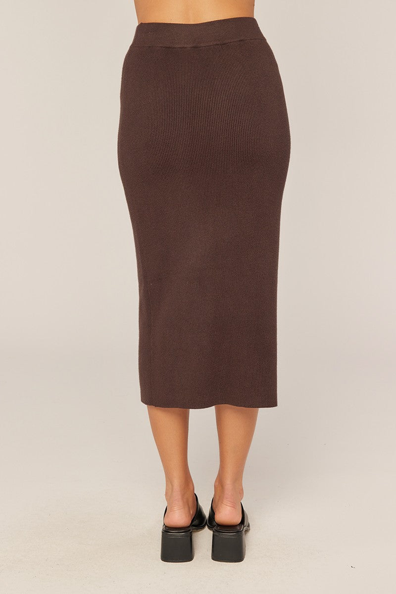 woman wearing a brown ribbed midi skirt, viewed from the back, with a fitted silhouette and high waist