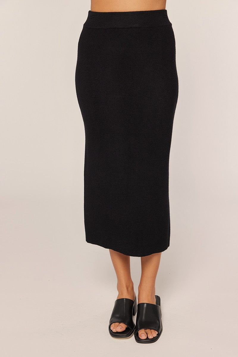 woman wearing a black ribbed midi skirt with a fitted waistband and open-toe black sandals