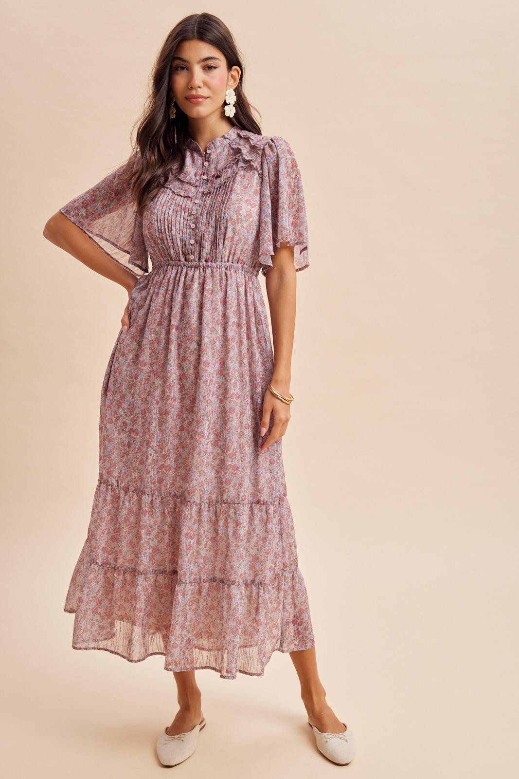 woman wearing a pink floral maxi dress with short flutter sleeves and tiered ruffles at the hem