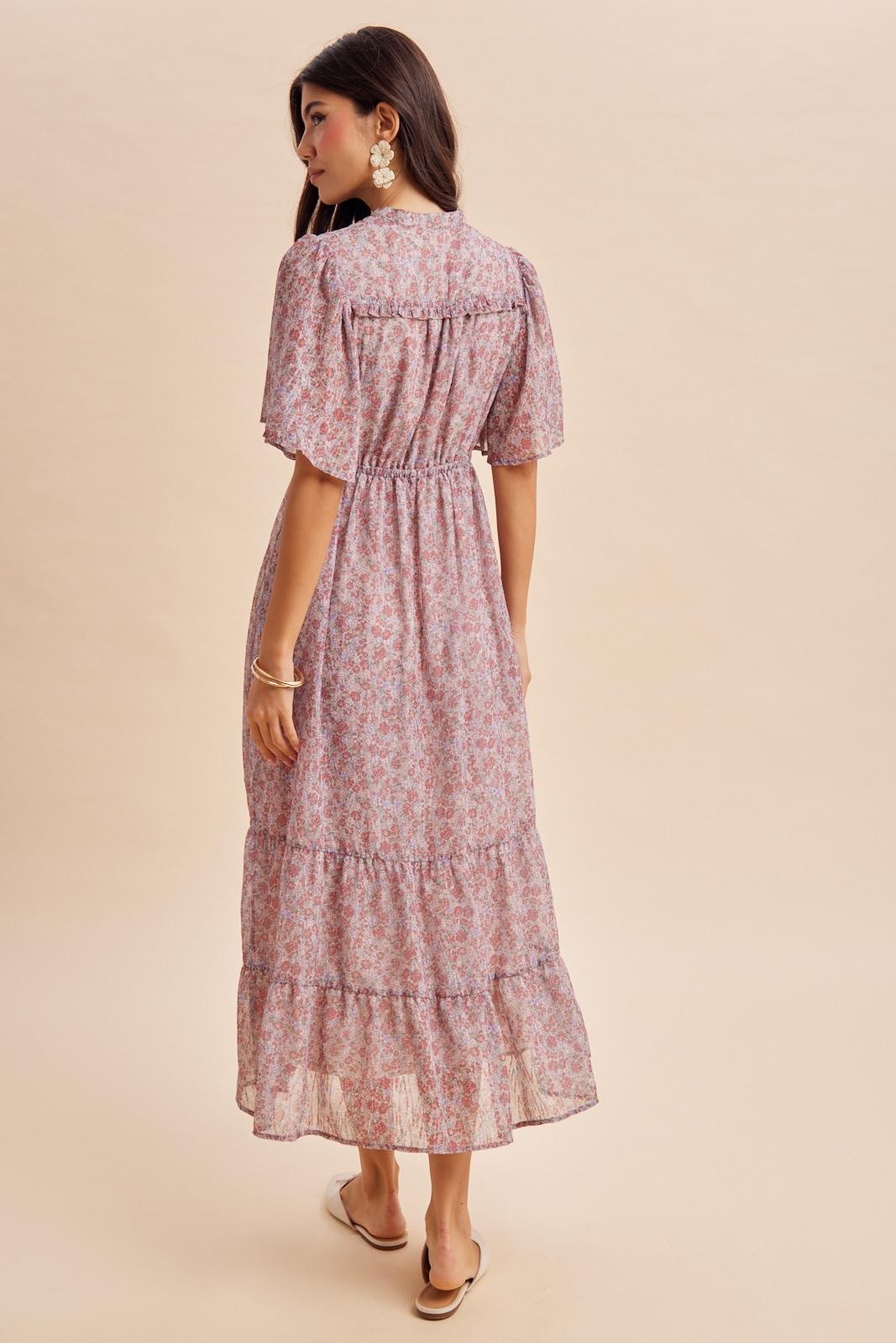 woman wearing a pink floral maxi dress with short puff sleeves and a tiered skirt, viewed from the back