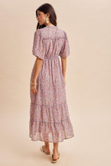woman wearing a pink floral maxi dress with short puff sleeves and a tiered skirt, viewed from the back