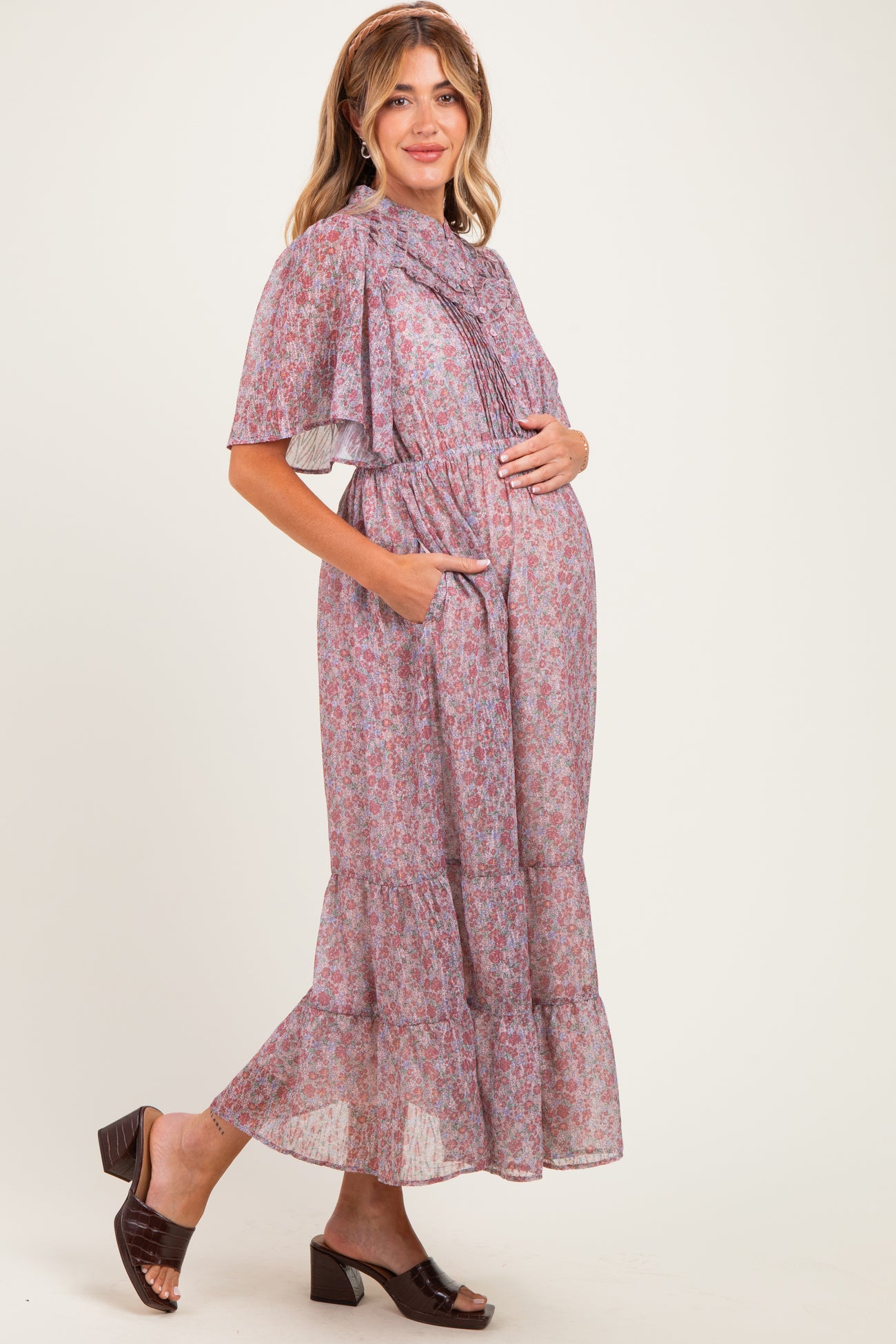woman wearing a lavender floral maxi maternity dress with short sleeves and pockets, holding her baby bump