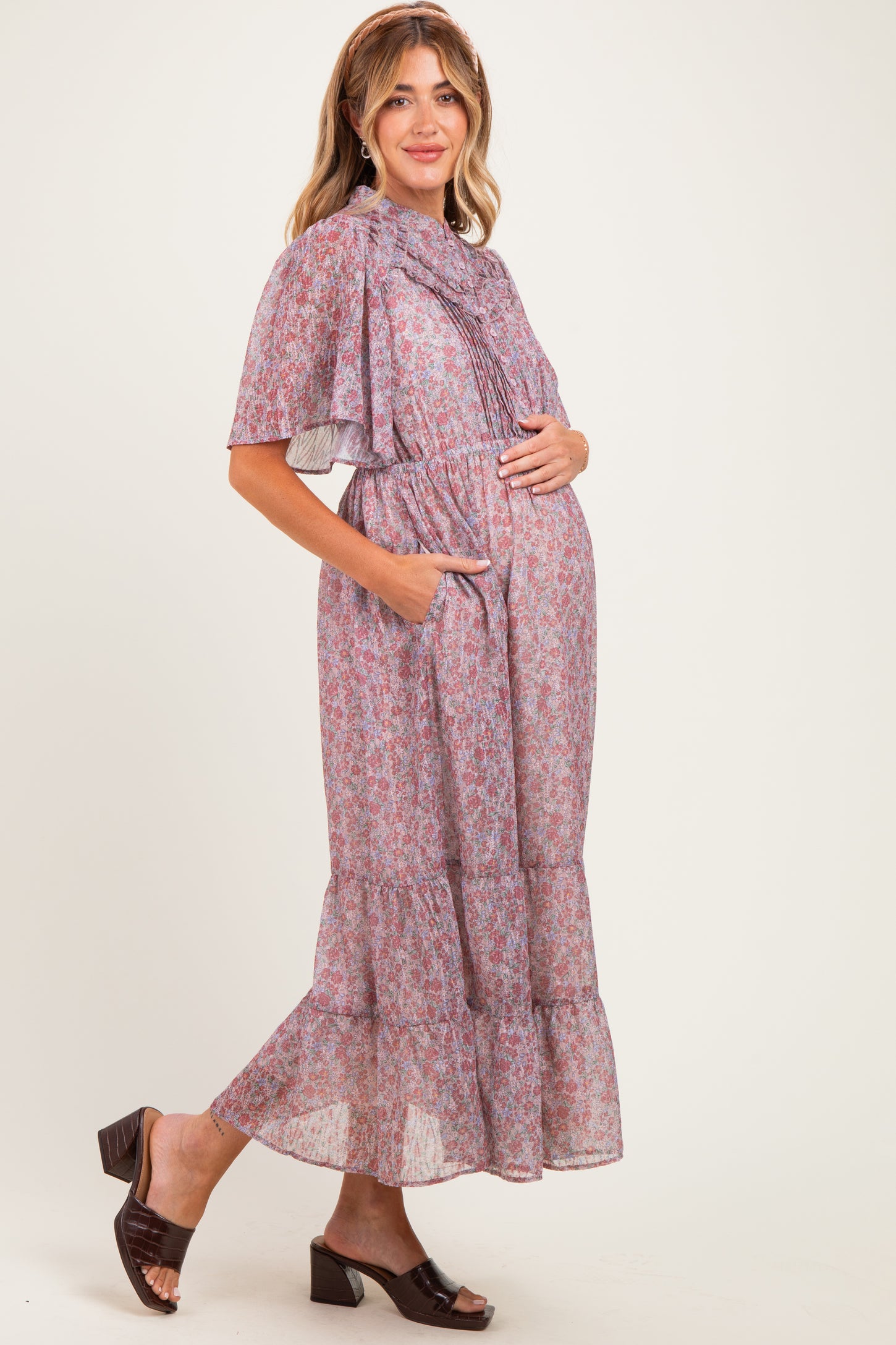 woman wearing a lavender floral maxi maternity dress with short sleeves and pockets, holding her baby bump