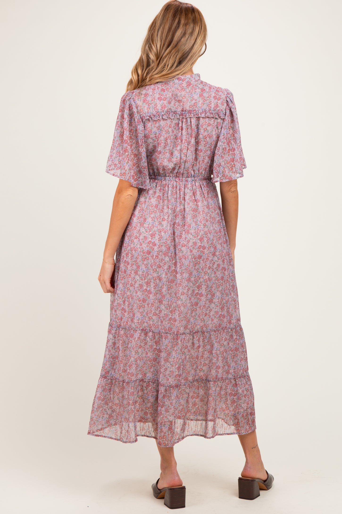 woman wearing a floral maternity maxi dress with short sleeves and a tiered skirt, showing her baby bump from the back