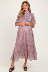 woman wearing a floral print maternity dress with puff sleeves and a tiered hem, showing her baby bump