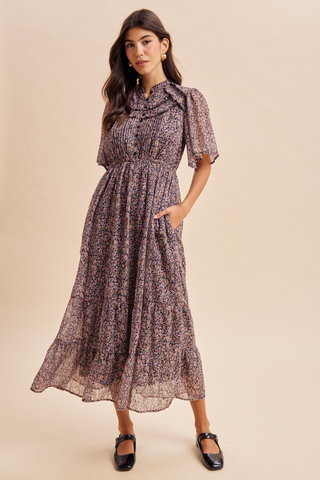 woman wearing a floral patterned maxi dress with short sleeves and pockets, styled with black flats