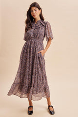 woman wearing a floral patterned maxi dress with short sleeves and pockets, styled with black flats