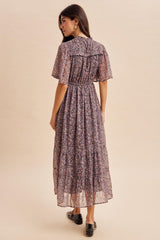 woman wearing a back view of a floral print maxi dress with puff sleeves and a flowy skirt