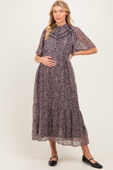 woman wearing a floral maternity maxi dress with short sleeves and a ruffled neckline, holding her baby bump