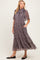 woman wearing a floral print maternity dress with short sleeves and a ruffled neckline, featuring pockets and a flowing skirt