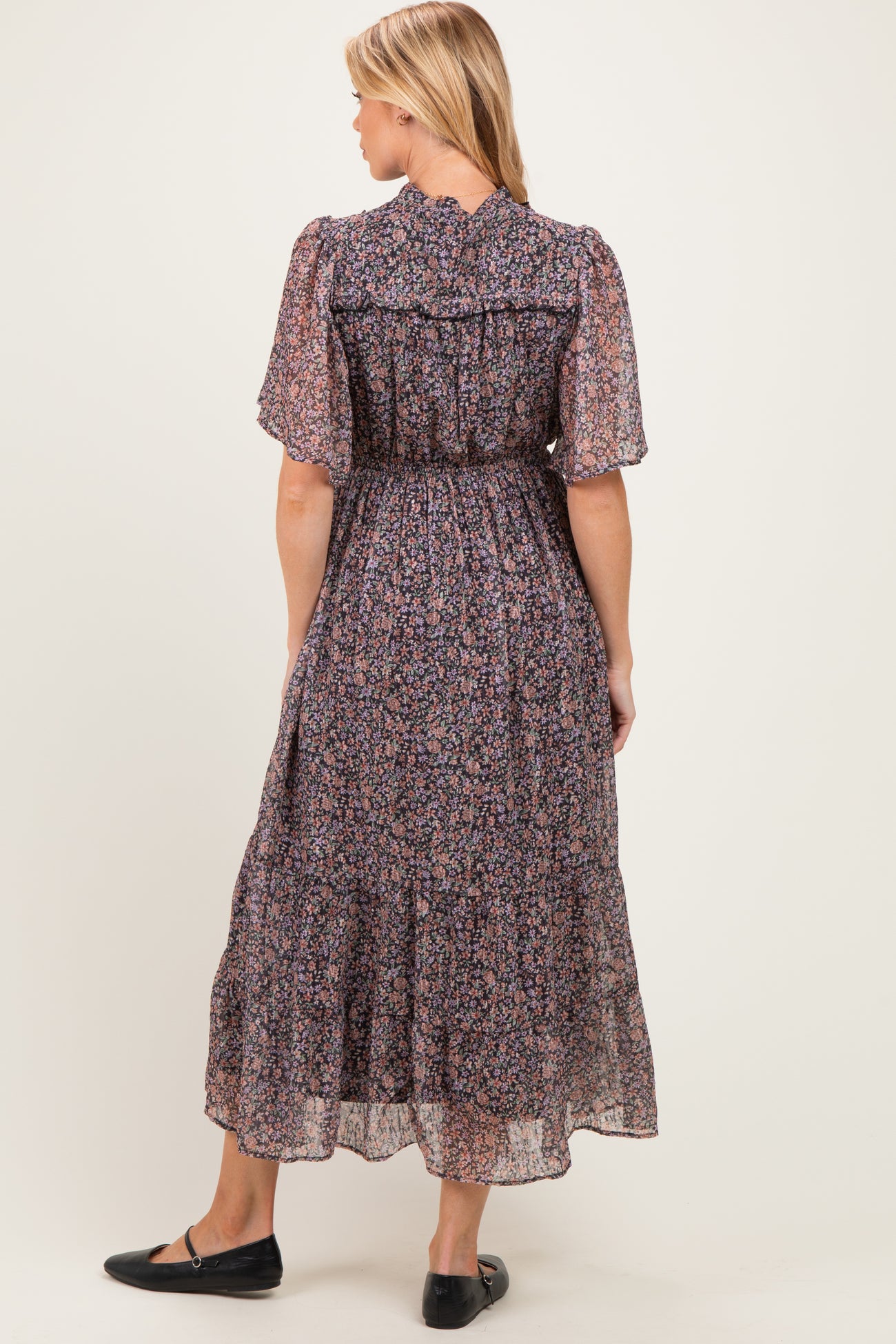 woman wearing a floral print maternity maxi dress with short flutter sleeves and a smocked waist, viewed from the back