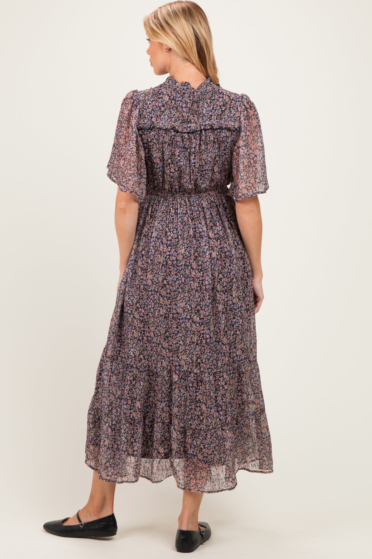 woman wearing a floral print maternity maxi dress with short flutter sleeves and a smocked waist, viewed from the back