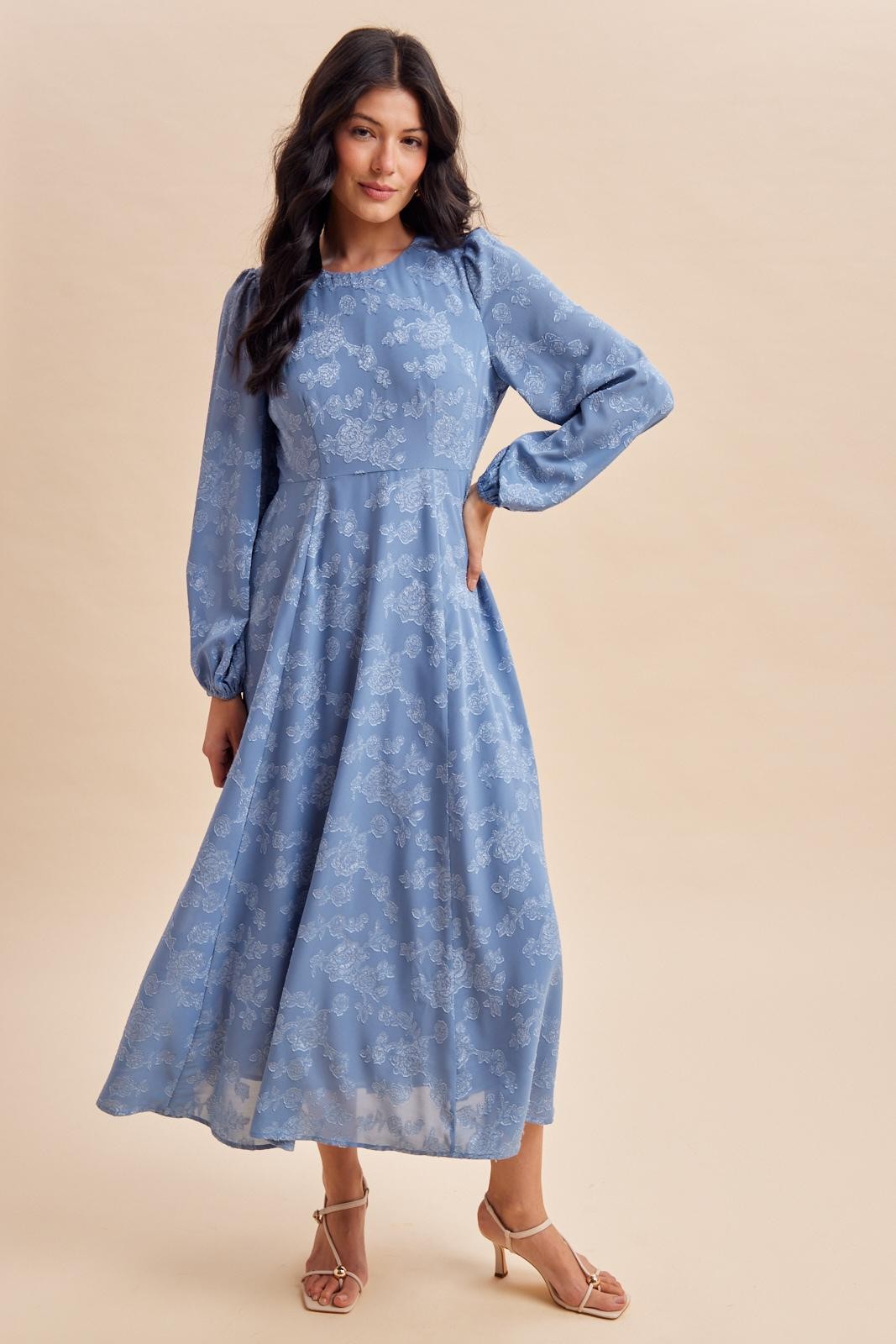 woman wearing a light blue floral maxi dress with long sleeves and a fitted bodice