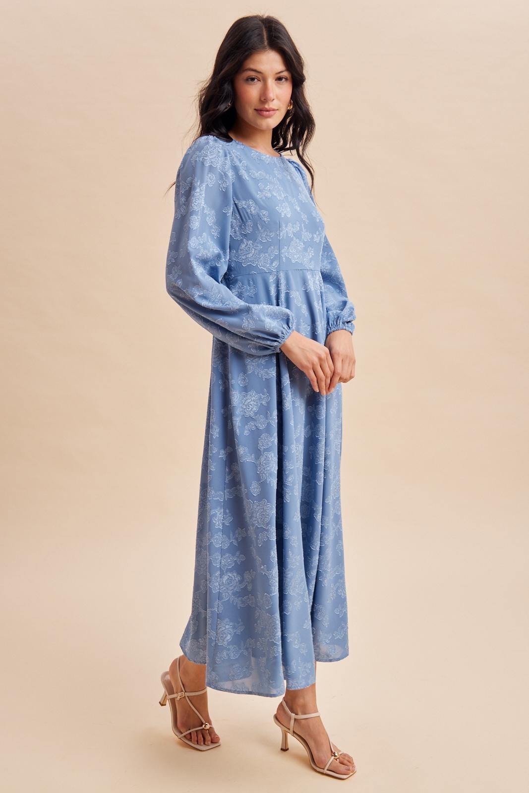woman wearing a light blue long sleeve floral maxi dress with puff sleeves and a cinched waist