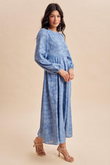woman wearing a light blue long sleeve floral maxi dress with puff sleeves and a cinched waist