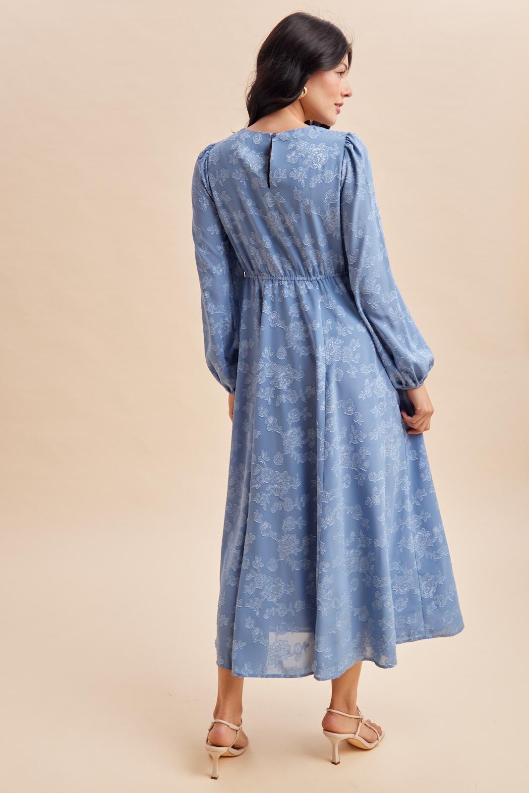 woman wearing a light blue floral long sleeve maxi dress with a cinched waist and flowy skirt