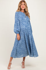woman wearing a light blue floral maternity dress with balloon sleeves and a flowing skirt