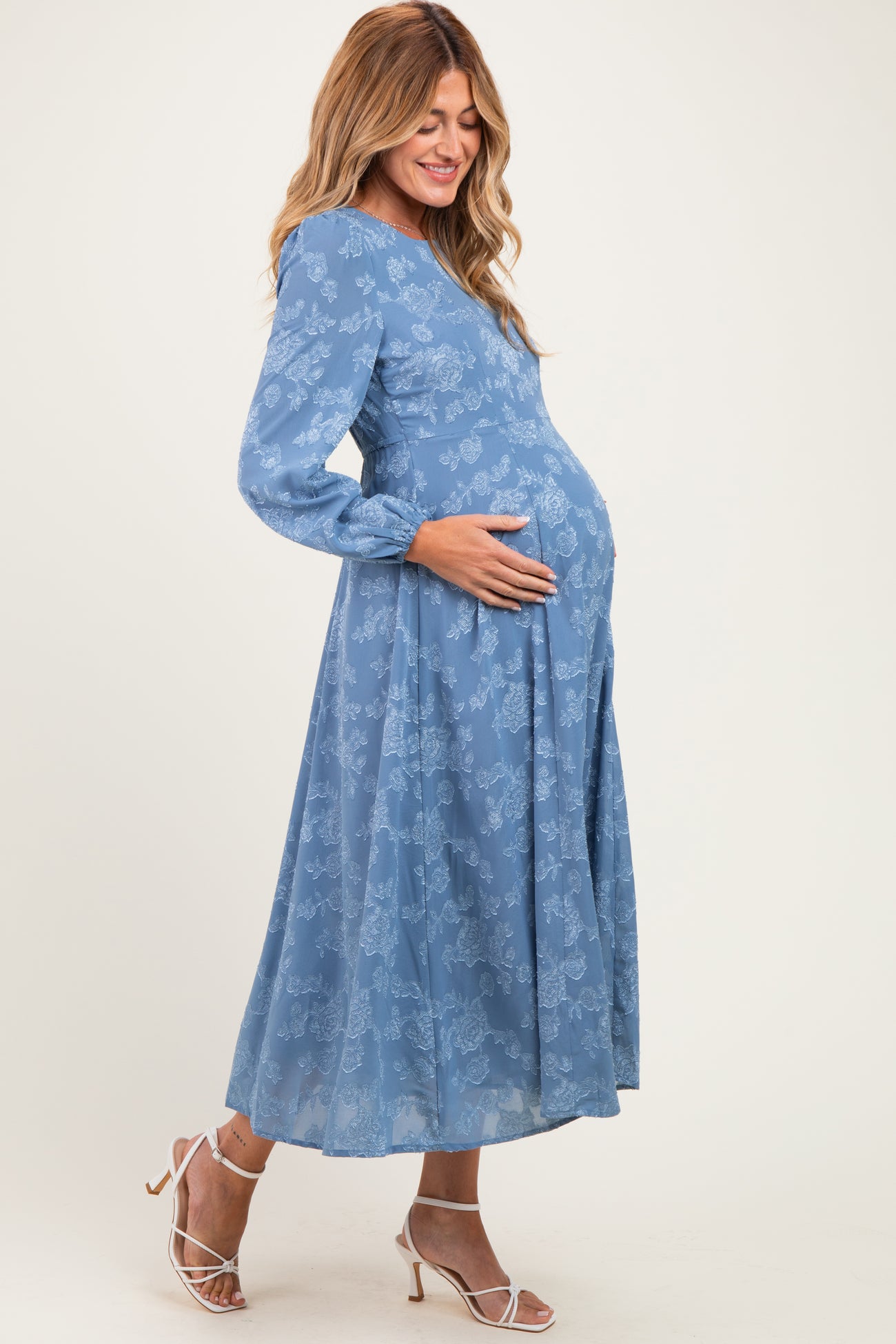 woman wearing a blue floral maternity dress with long sleeves and a visible baby bump