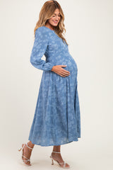 woman wearing a blue floral maternity dress with long sleeves and a visible baby bump