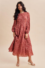 woman wearing a rust colored floral midi dress with puff sleeves and a flowy silhouette