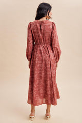 woman wearing a dusty rose floral long sleeve maxi dress with a cinched waist viewed from the back