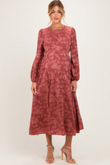 woman wearing a rose patterned maternity dress with long sleeves and a flowing skirt, showing her baby bump