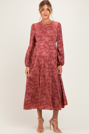 woman wearing a rose patterned maternity dress with long sleeves and a flowing skirt, showing her baby bump