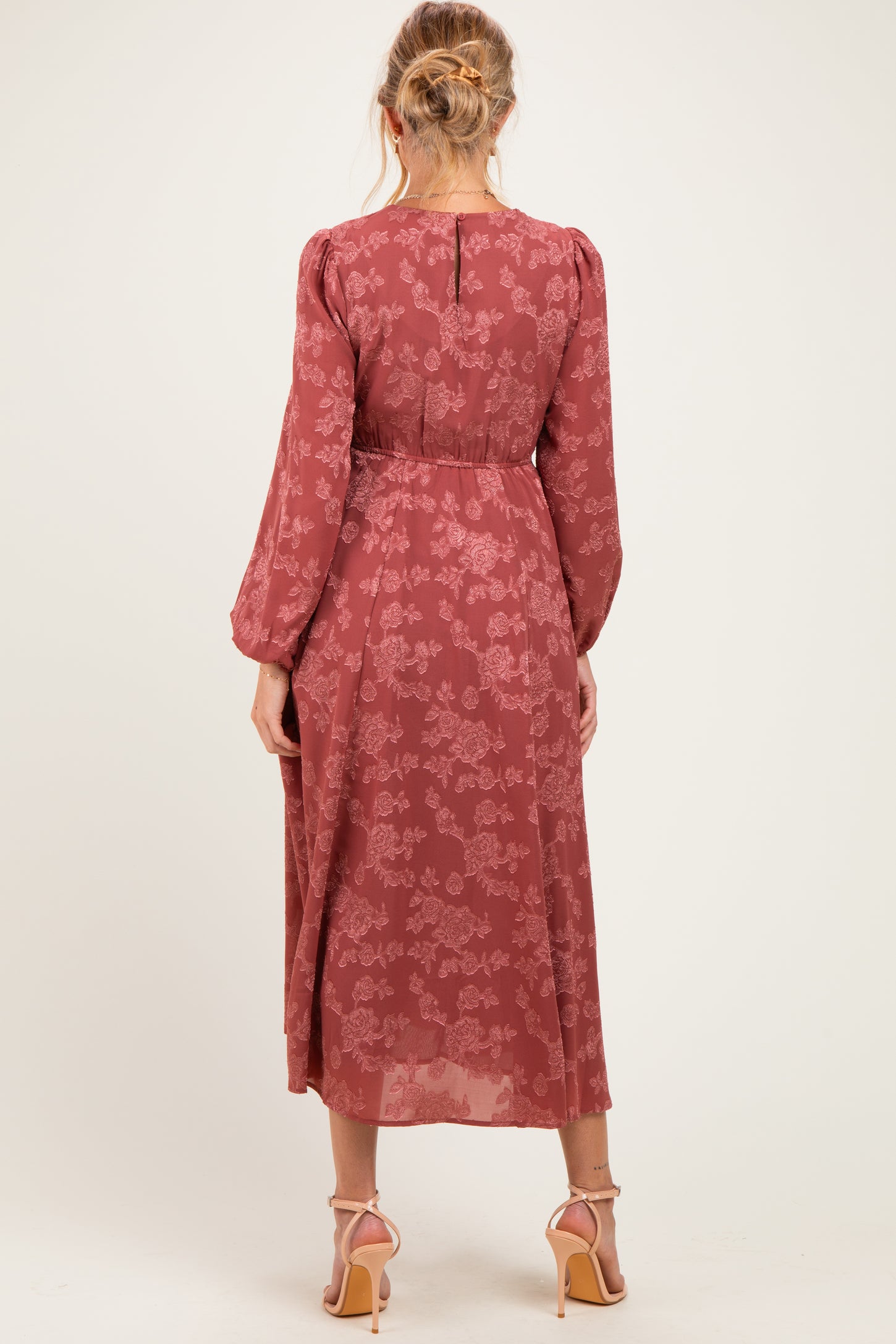 woman wearing a rust floral long sleeve maternity dress with a flowing silhouette and back button detail