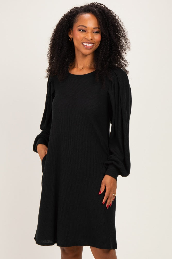 woman wearing a black long sleeve knit dress with puffed sleeves and a relaxed fit