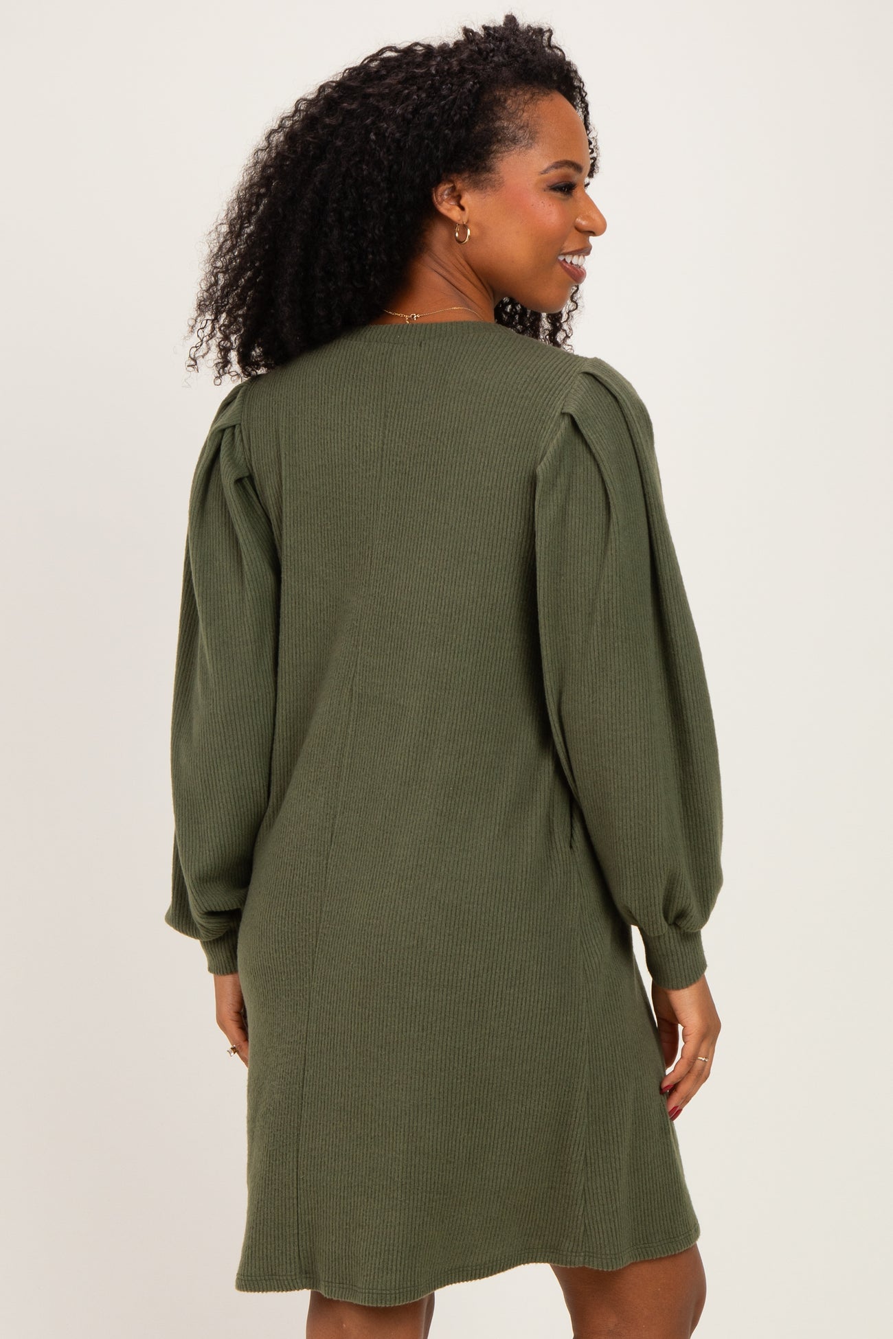 woman wearing a dark green long sleeve sweater dress with puffed sleeves and a relaxed fit