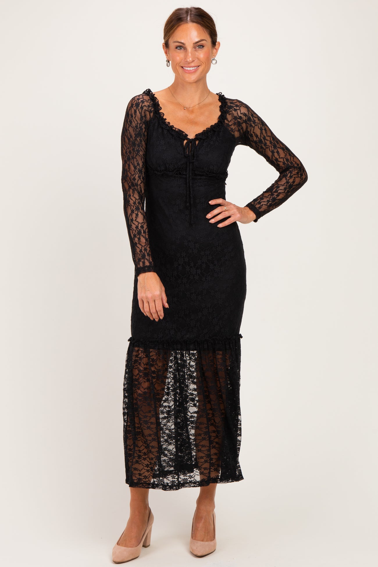woman wearing a black lace maxi dress with long sleeves and a ruffled hem, posing with a smile