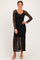 woman wearing a black lace maxi dress with long sleeves and a ruffled hem, posing with a smile