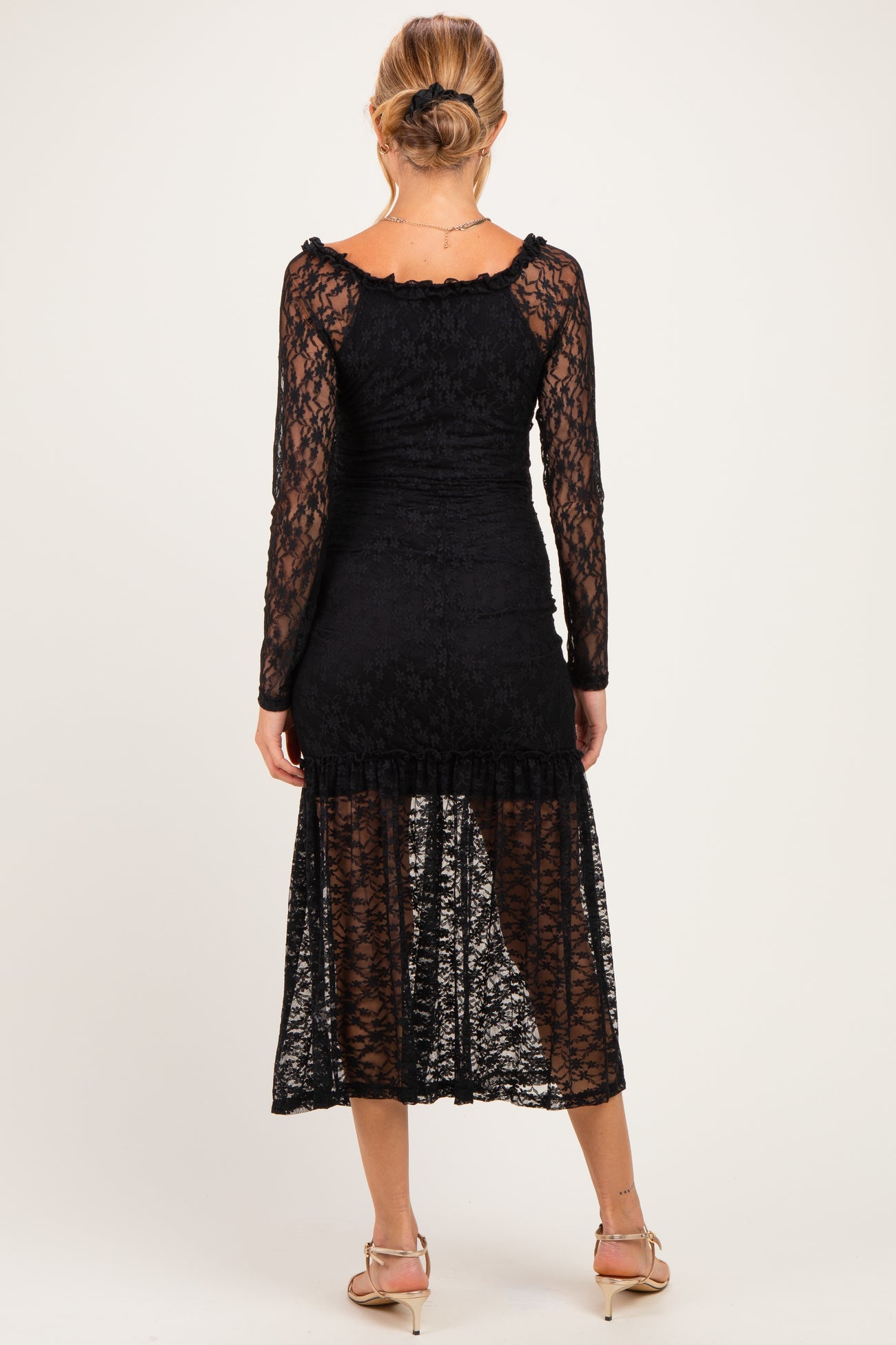 woman wearing a black lace maternity dress with long sleeves and a mid-length hem, showing a form-fitting silhouette