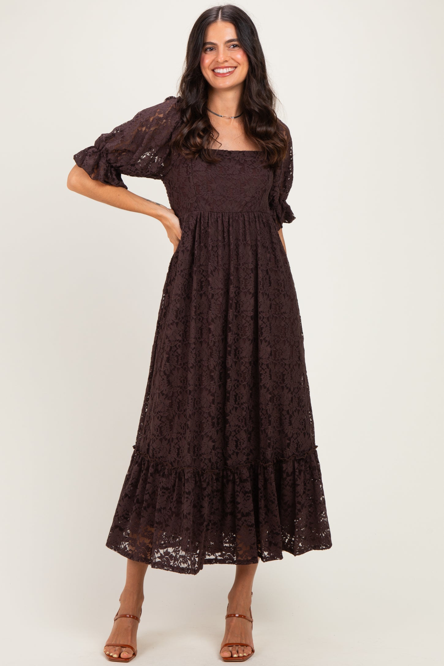 woman wearing a chocolate brown lace maxi dress with puff sleeves and a tiered hem
