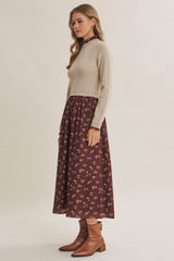woman wearing a beige cropped sweater with a burgundy floral maxi dress and brown ankle boots