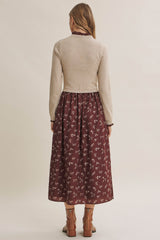 woman wearing a beige long sleeve sweater over a burgundy floral maxi dress, viewed from the back