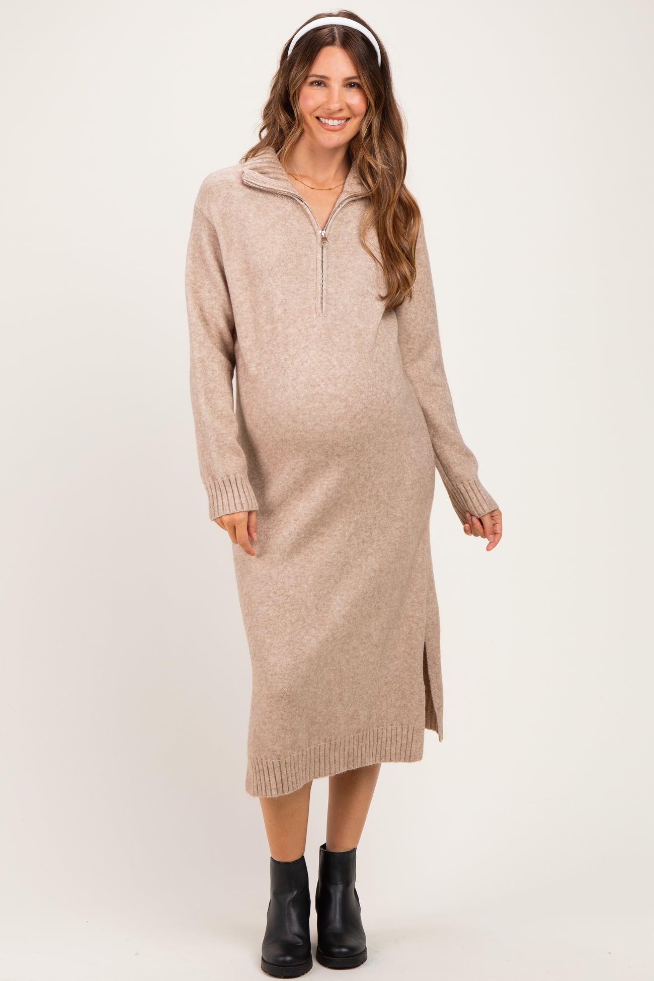 woman wearing a beige zip-up maternity sweater dress with side slits and a baby bump visible