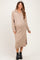 woman wearing a beige zip-up maternity sweater dress with side slits and a baby bump visible