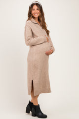woman wearing a beige maternity sweater dress with a side slit and a visible baby bump.