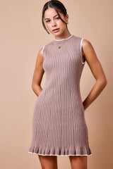 woman wearing a dusty pink sleeveless ribbed knit dress with a flared hem and white trim details