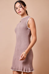 woman wearing a ribbed taupe sleeveless dress with white trim and a ruffled hem, styled with minimal jewelry