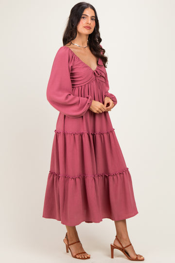 woman wearing a dusty pink long sleeve tiered midi dress with a deep v-neckline and puff sleeves