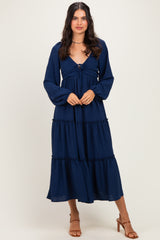 woman wearing a navy blue tiered maxi dress with long sleeves and a front tie detail