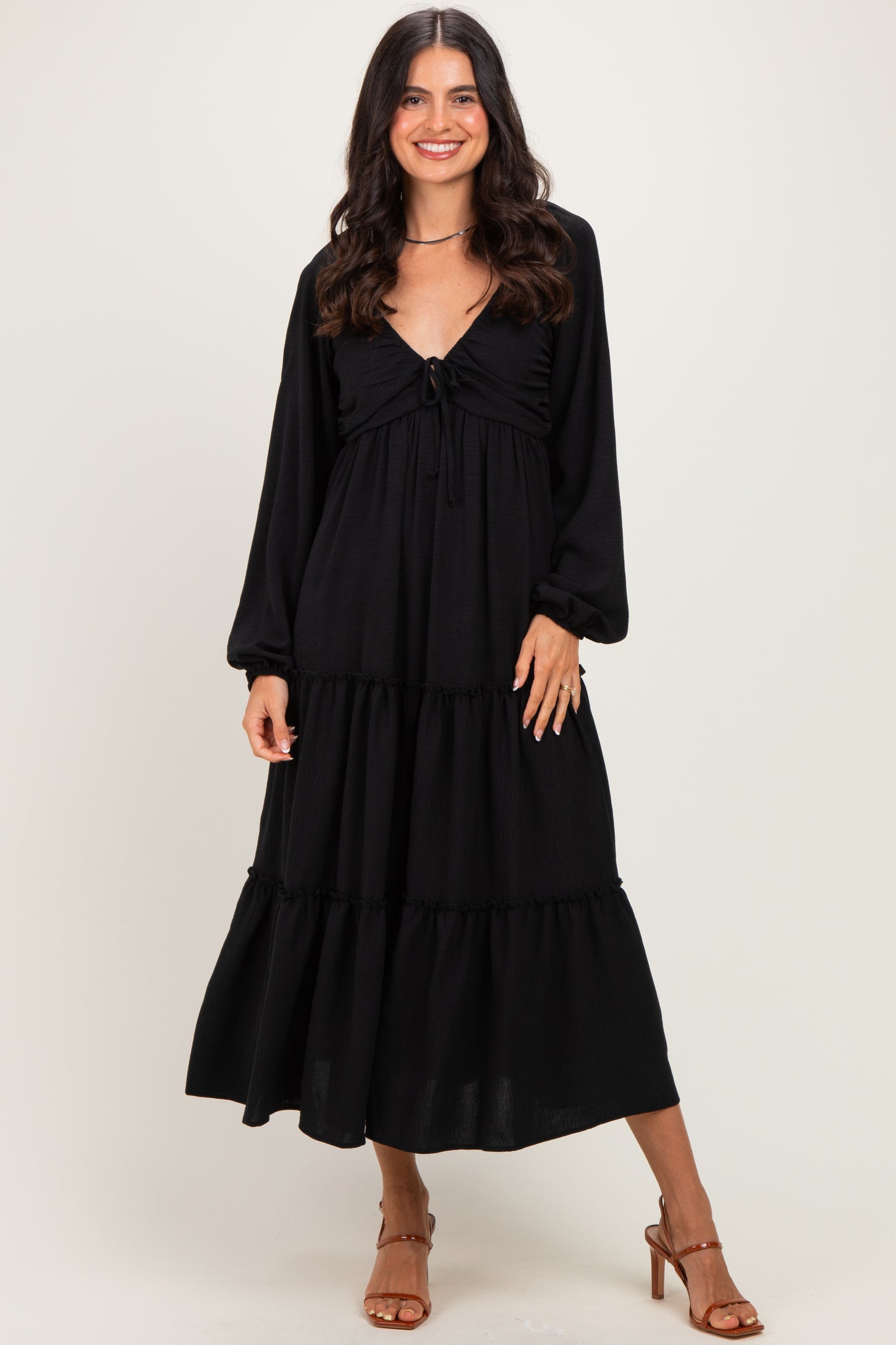 woman wearing a black long sleeve maxi dress with a tie-front and tiered skirt