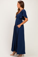 woman wearing a navy blue maxi dress with flutter sleeves and side pockets