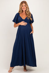 woman wearing a navy blue maxi maternity dress with short flutter sleeves and a baby bump visible