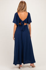 woman wearing a navy blue maternity maxi dress with a tie-back detail and short sleeves, showing a stylish open back