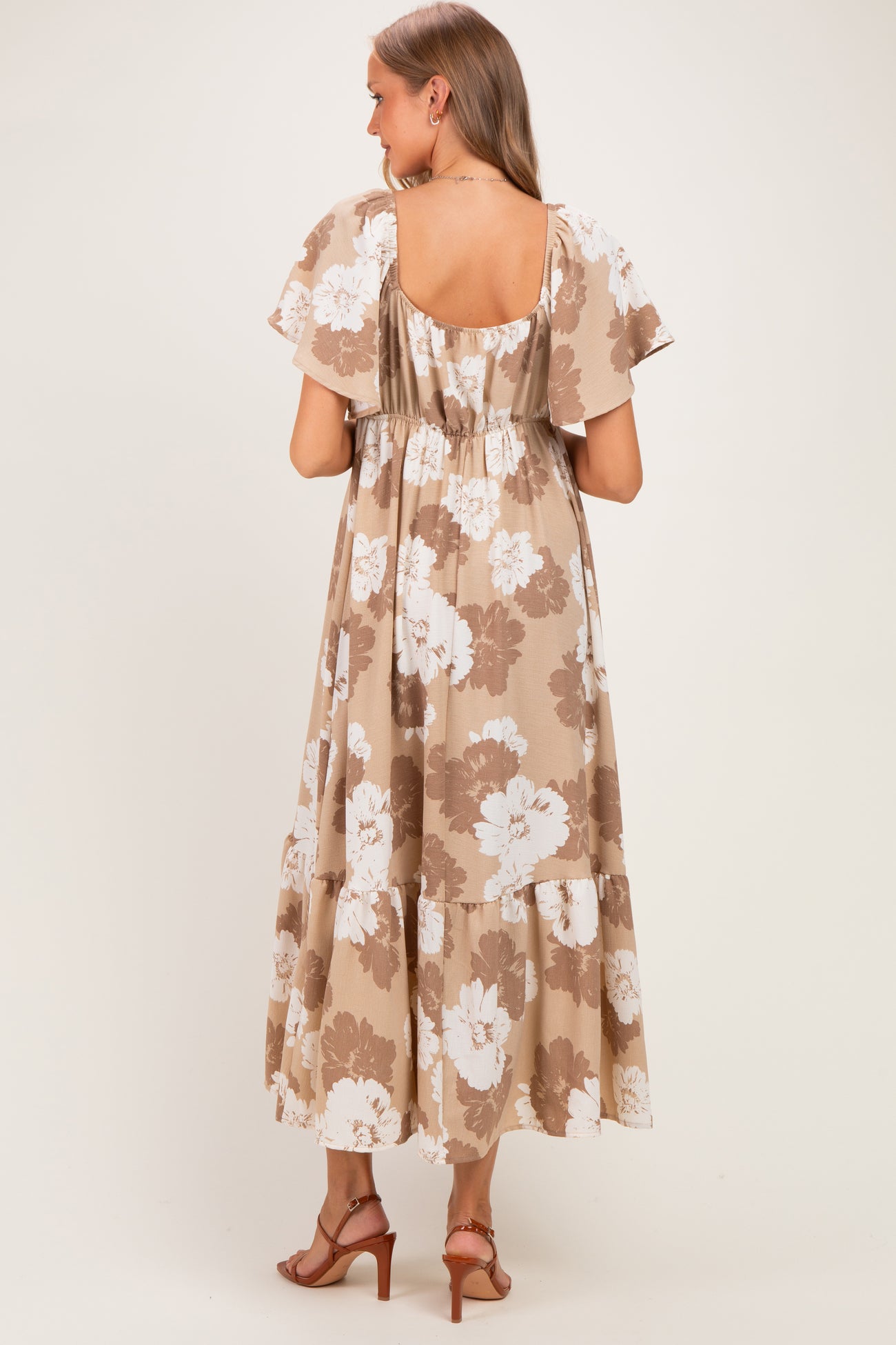 woman wearing a floral print maternity maxi dress with a tiered skirt and flutter sleeves, showing her baby bump from the back