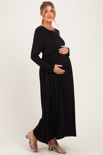 woman wearing a black long sleeve maternity dress with gathered waist, holding her baby bump